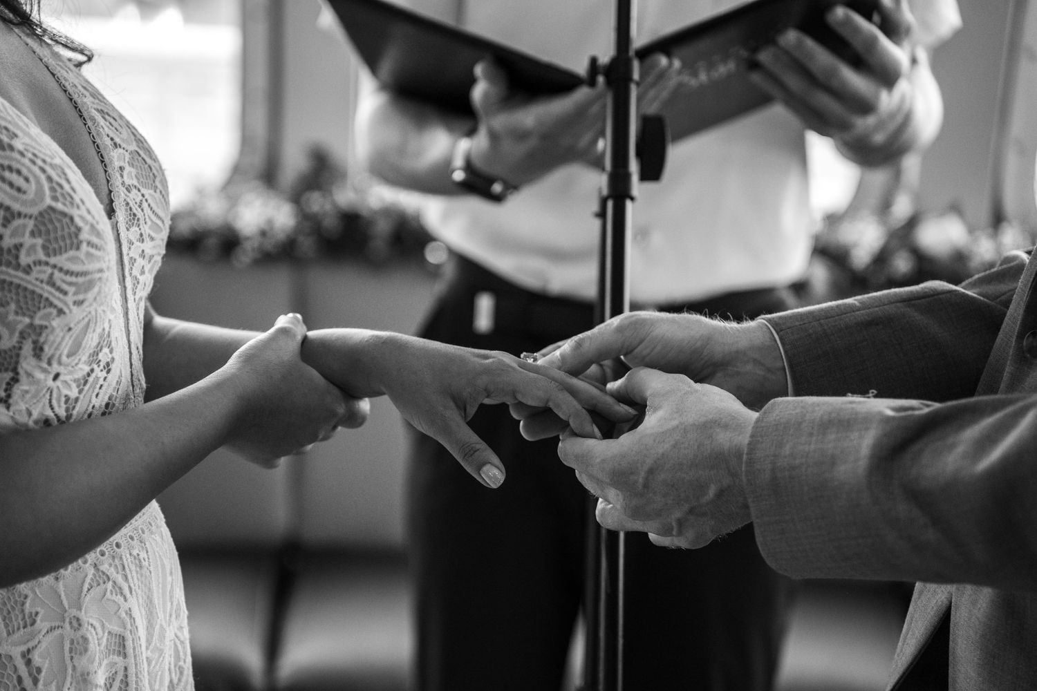 Close-up shot of hands exchanging wedding rings during an indoor ceremony. Micro wedding on Yacht StarShip in Tampa
