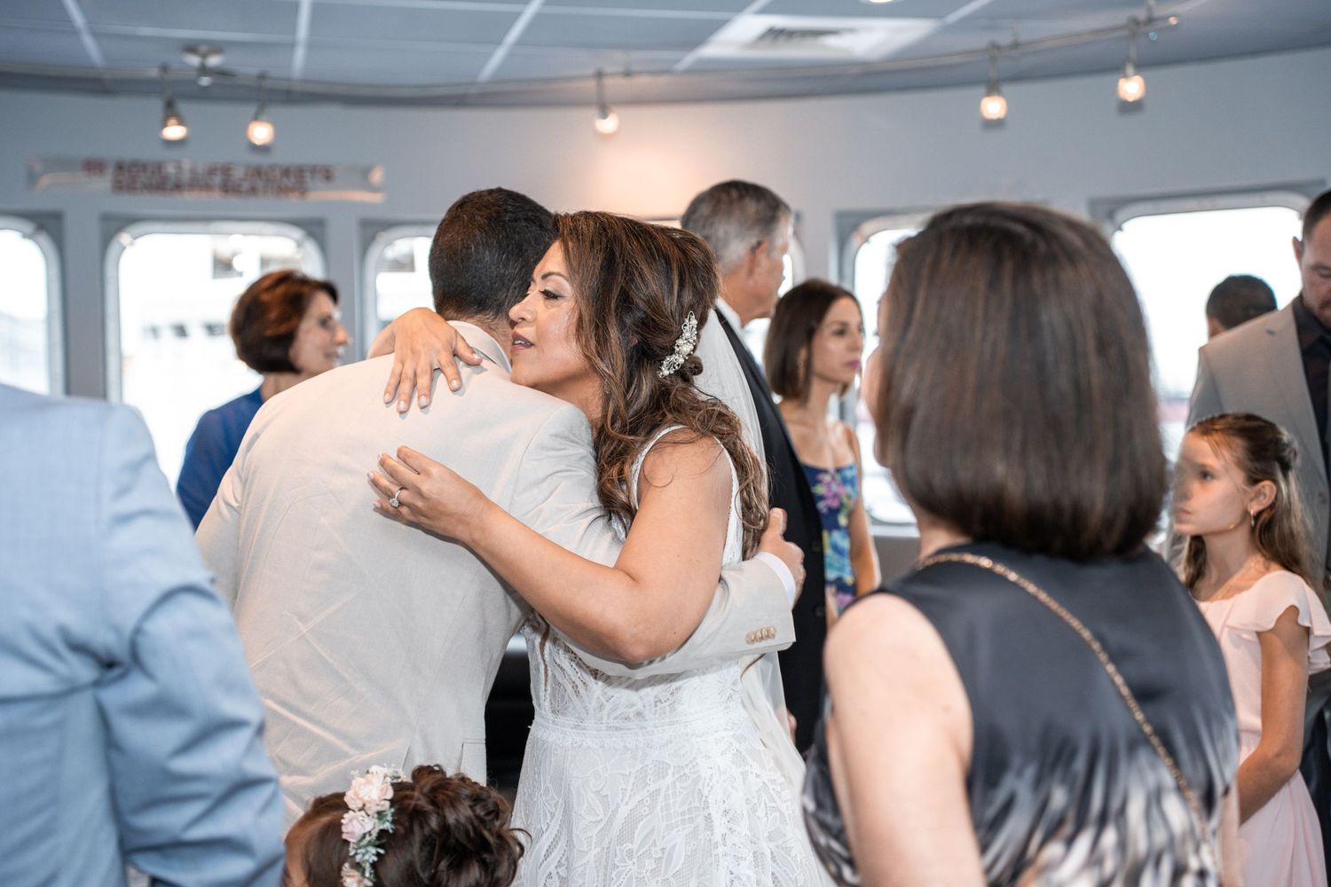Emotional embrace during wedding celebration in boat venue with guests looking on. Micro wedding on Yacht StarShip in Tampa