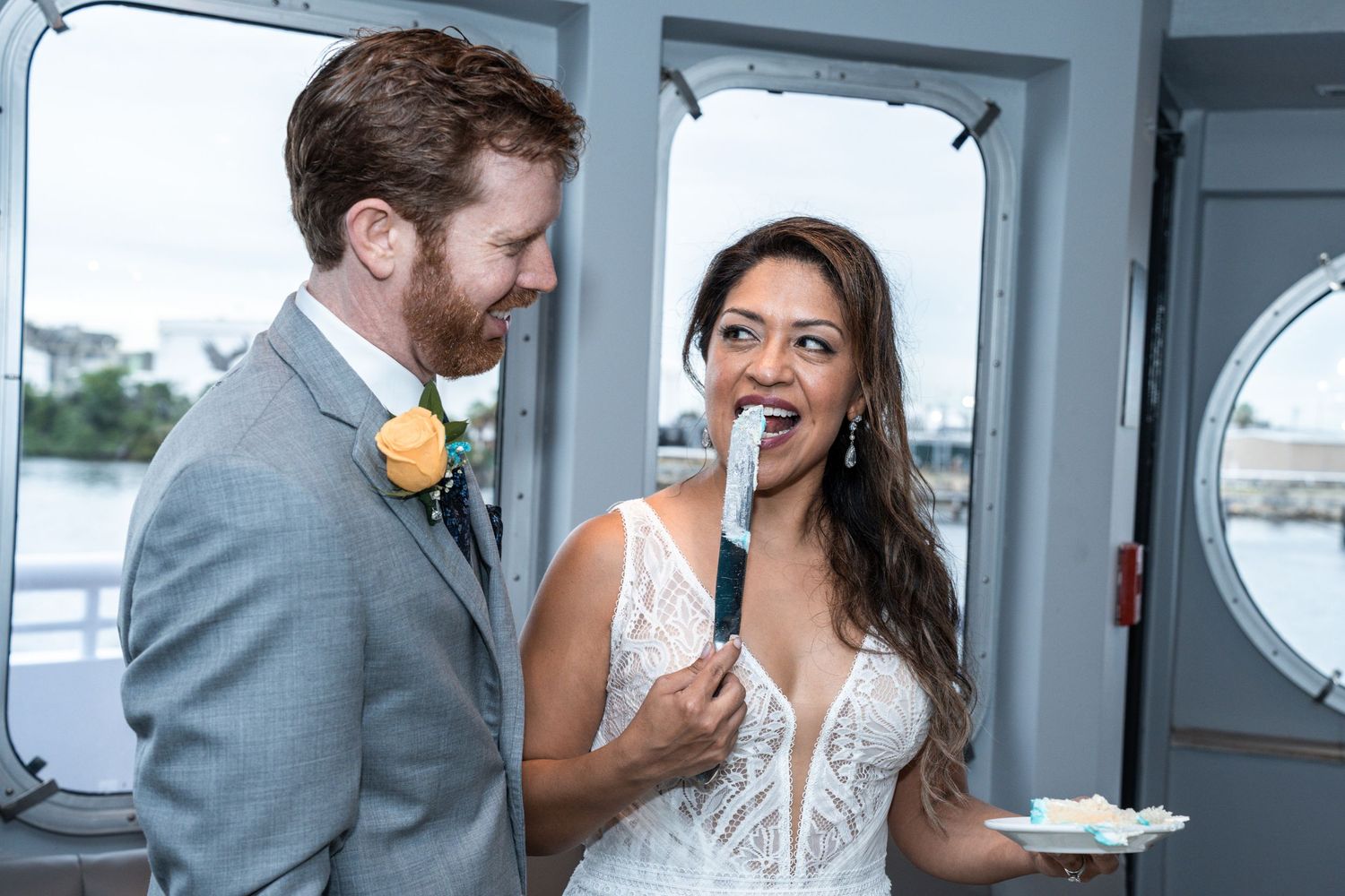 Couple sharing intimate moments and cake during their wedding reception by waterfront windows Yacht StarShip in Tampa Fl
