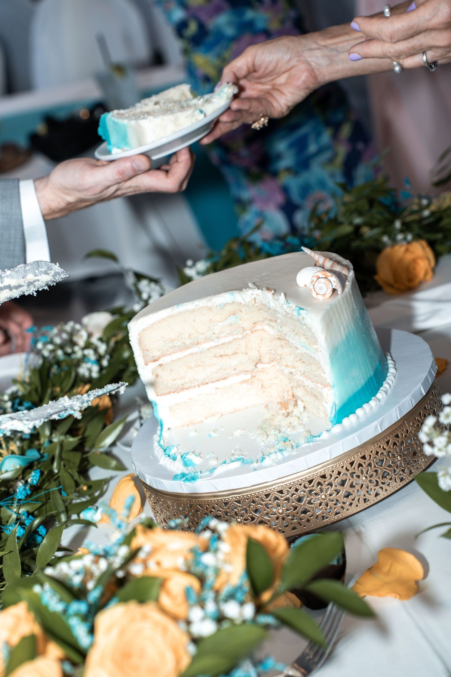 A slice of elegant blue ombre wedding cake being served  with greenery and floral decor at Yacht StarShip in Tampa Fl