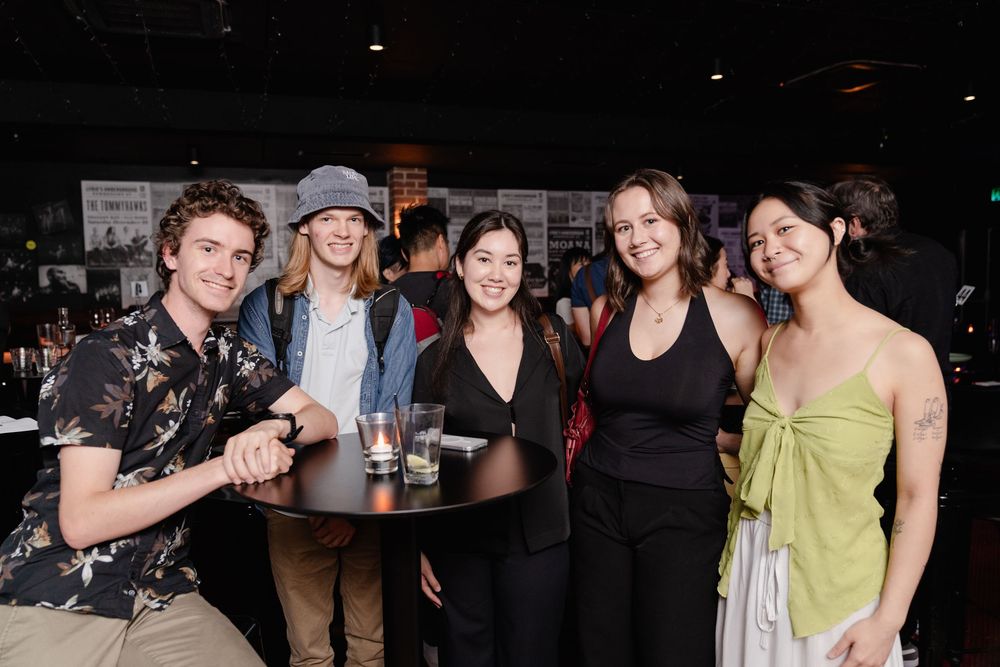 A group of friends socializing at a casual gathering in a dimly lit venue.