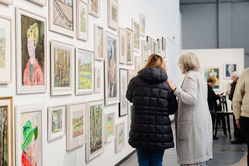 People viewing artwork displayed on gallery walls in an exhibition space.