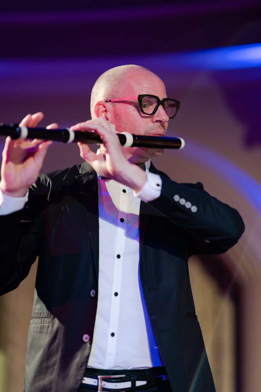 Conductor in formal attire gestures dramatically during a performance.