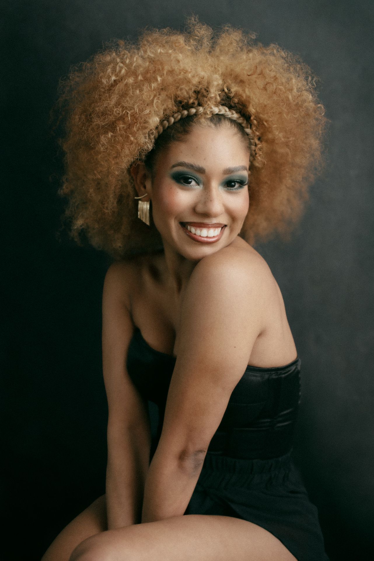 Elegant portrait featuring natural curly hair and black formal wear.