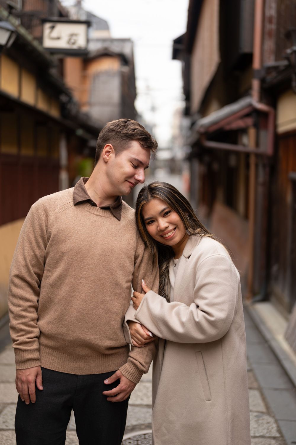 Happy couple embracing and smiling in a charming traditional Japanese street in Kyoto.