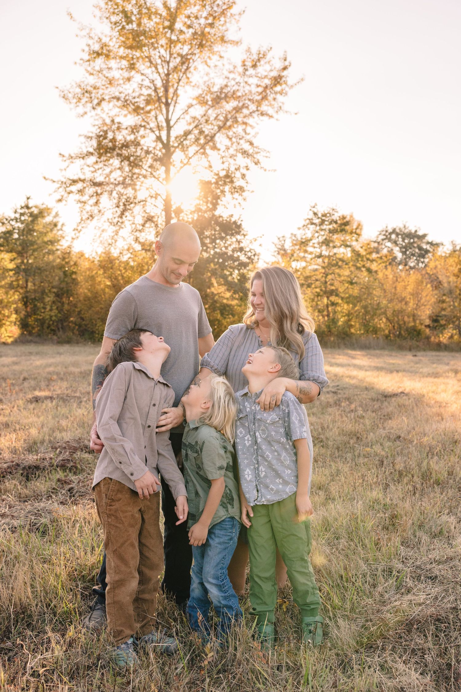 Family enjoying playful moments together in a golden sunset field.
