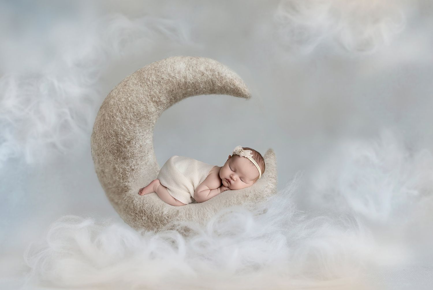 newborn boy posed in a flat basket filled with greenery. swaddled in maroon wearing a maroon and cream striped long tail sleepy cap.