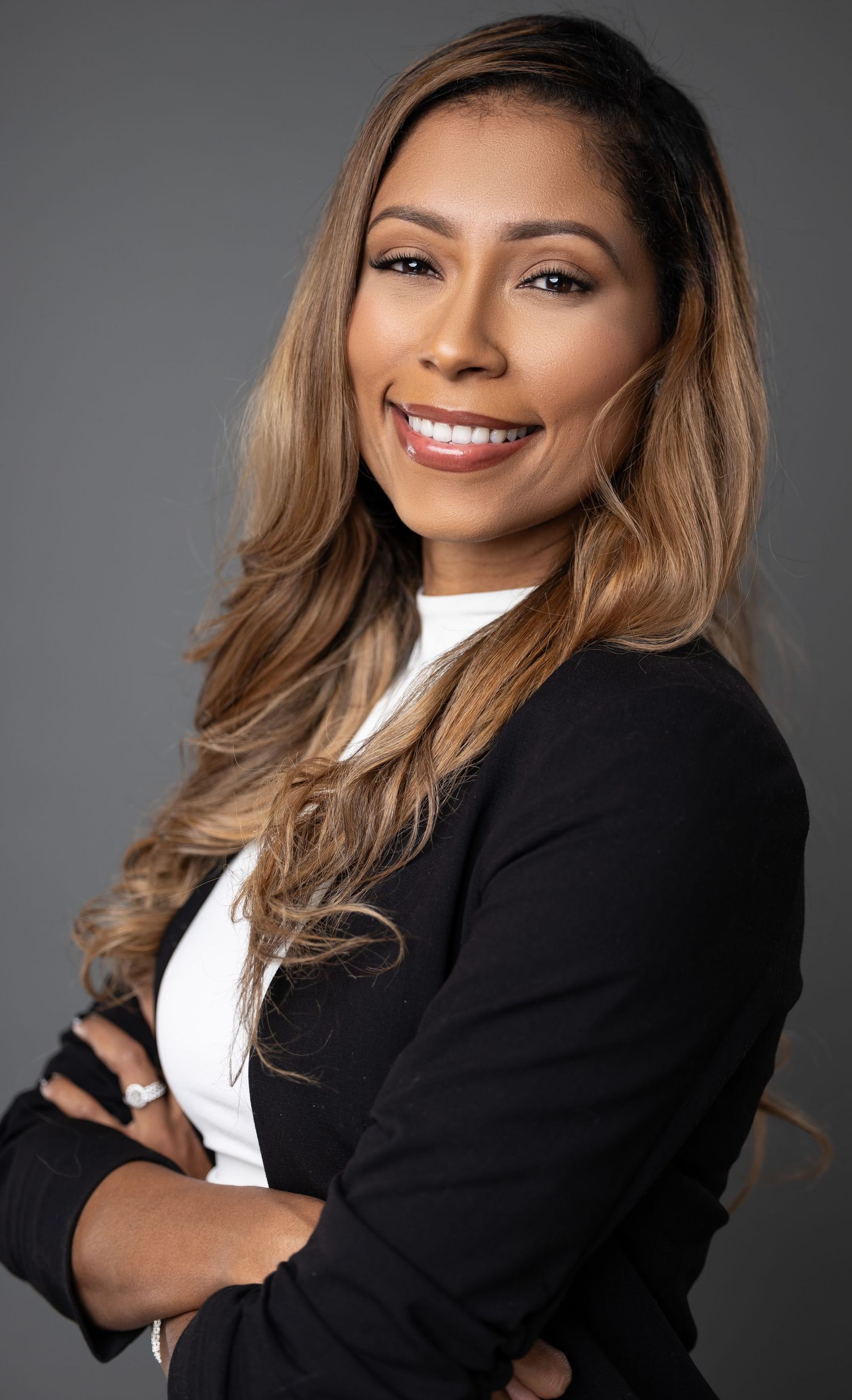 Professional headshots of someone in a black blazer and white top against a gray background showing different poses and expressions.