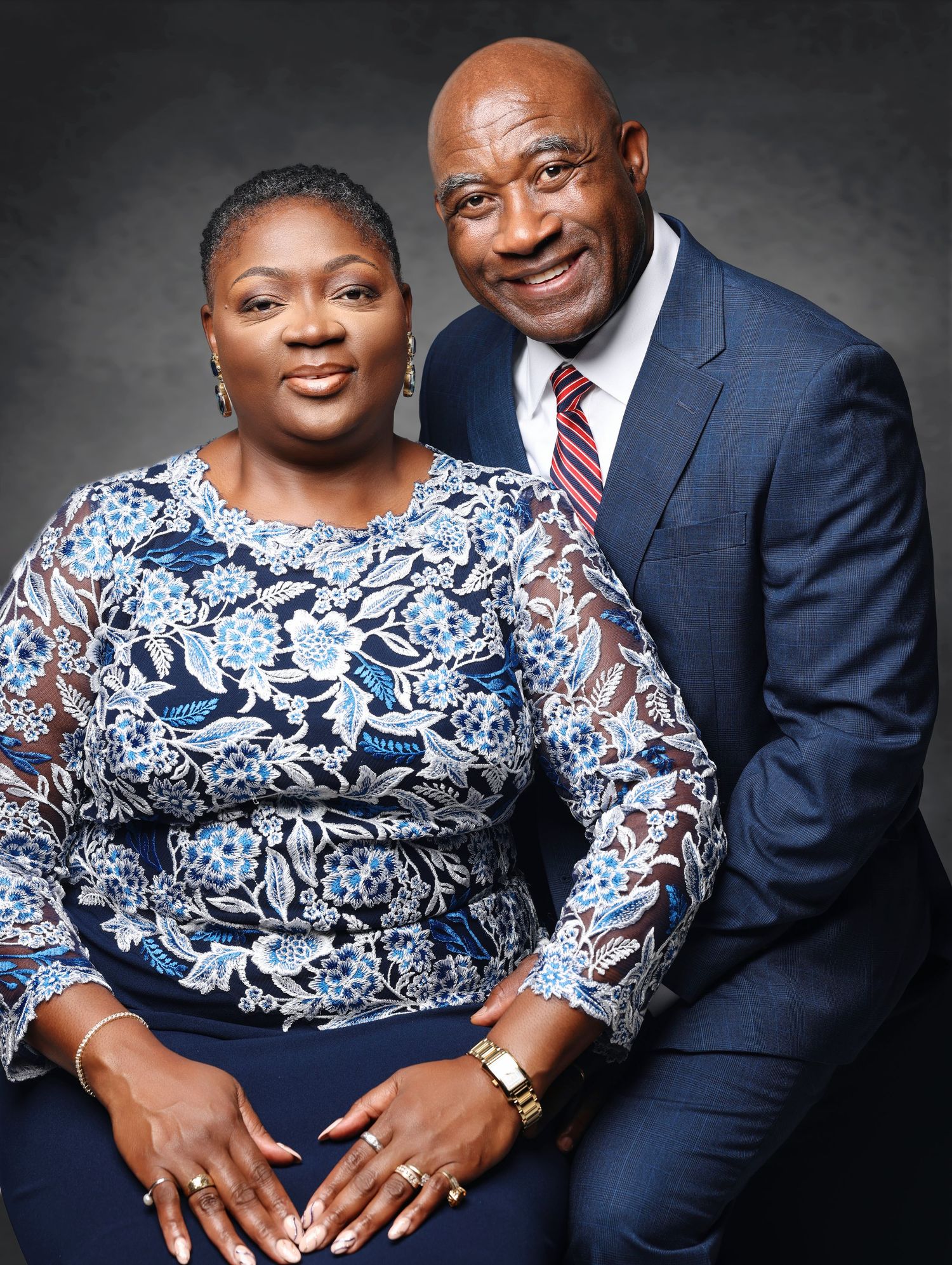 Professional studio portrait series showing a couple in formal attire with navy and white floral patterns against dark backdrop.