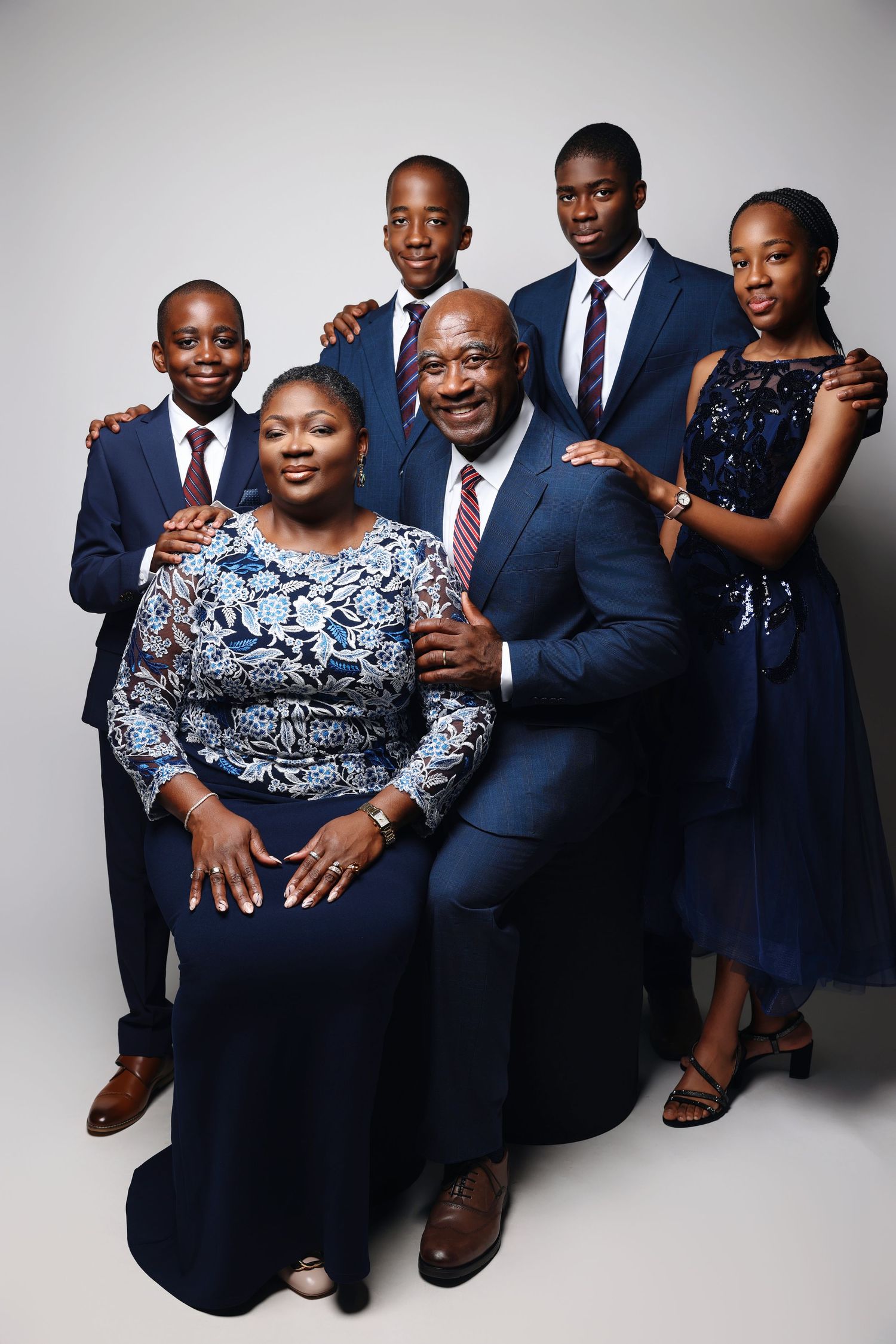 Professional studio portraits of a family in coordinated navy blue and black outfits against a neutral background.