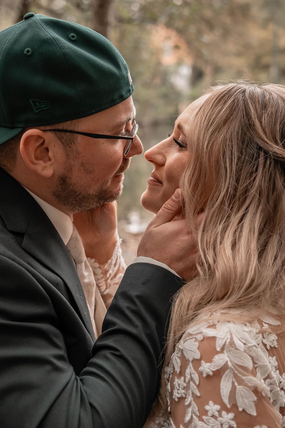 A romantic wedding moment captured outdoors with lace dress details and dark attire.