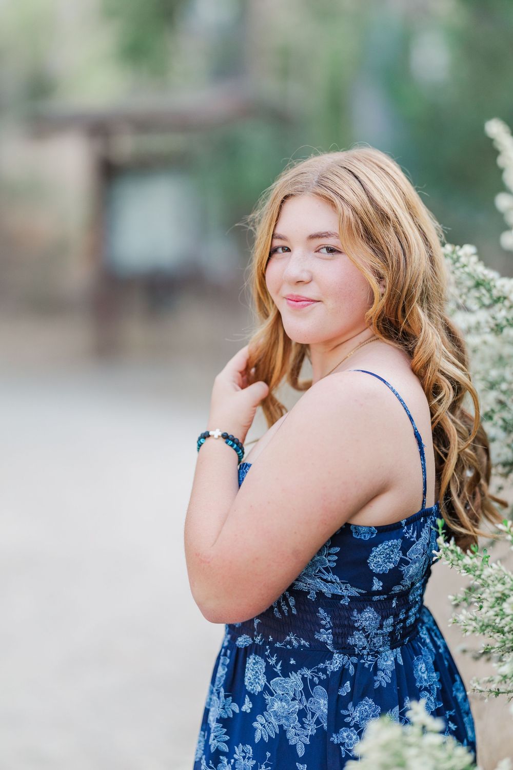 A series of outdoor portraits showing someone in a blue floral top posing against a natural backdrop with white flowers.