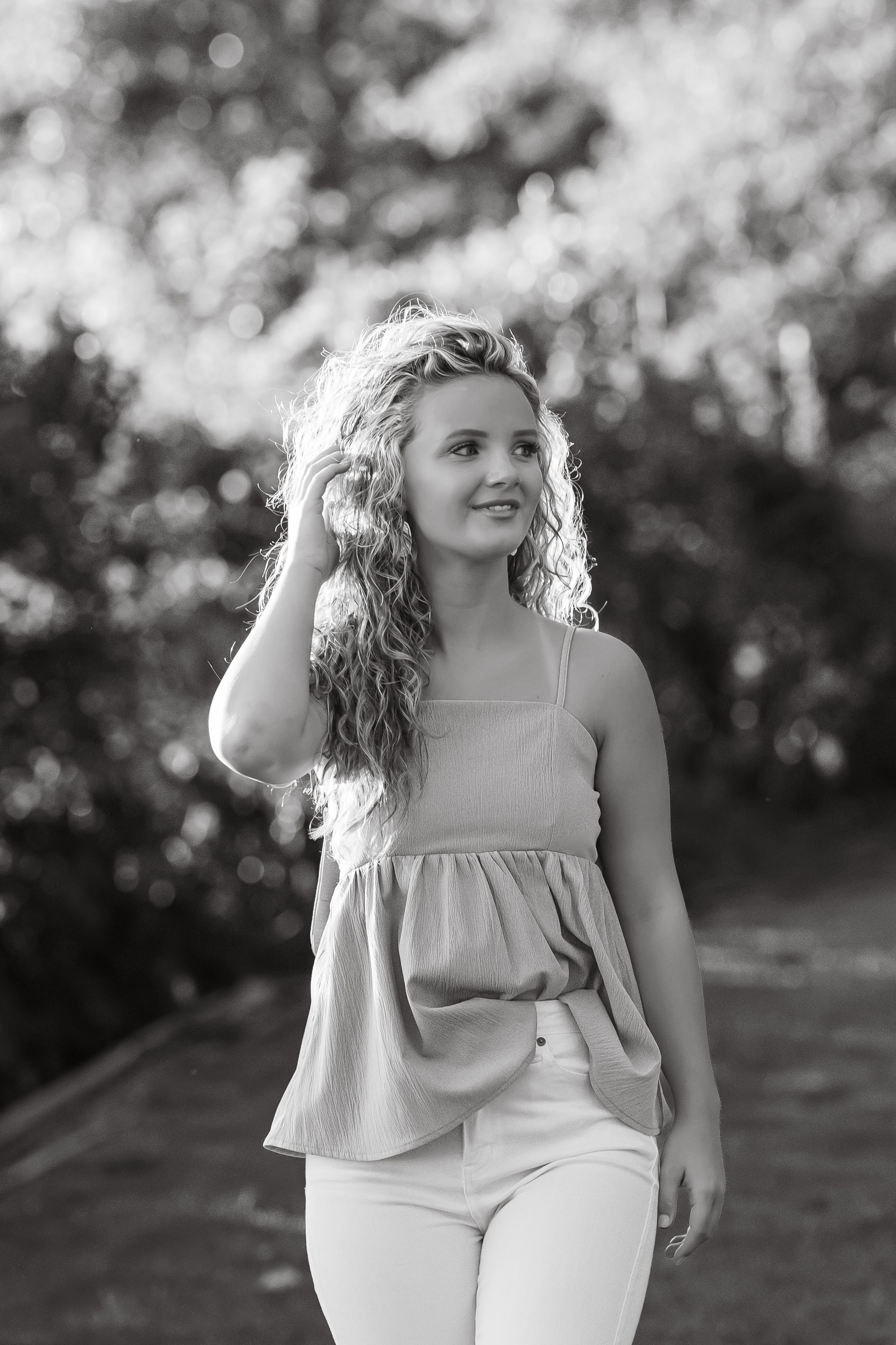 Black and white portrait in casual attire against natural background.