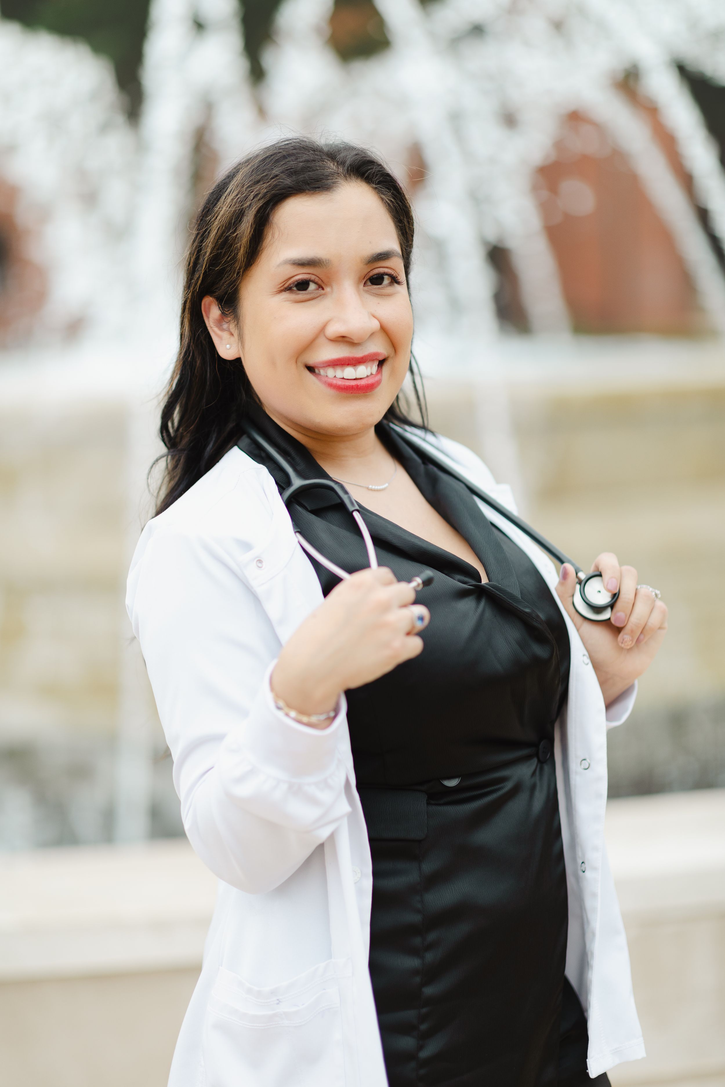 Graduate in white coat and black dress poses confidently for professional photos.
