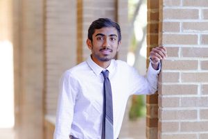 Professional headshots of someone in business attire against a brick wall background.