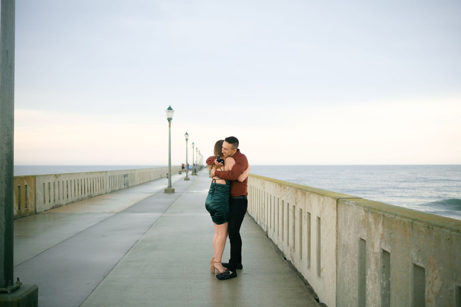 A couple shares romantic moments on a beachside pier during sunset.