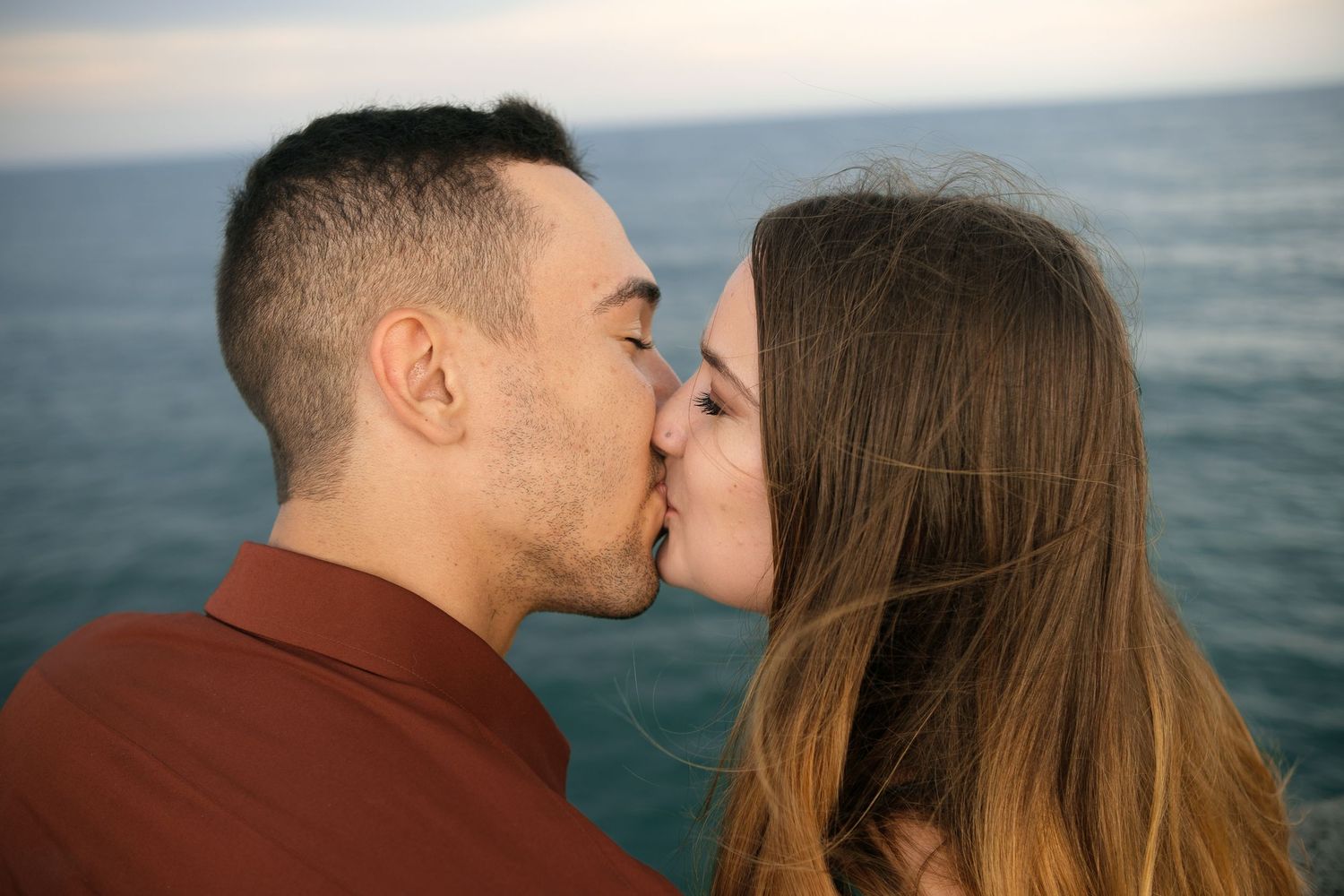 Romantic couple sharing intimate moments at sunset by the ocean.