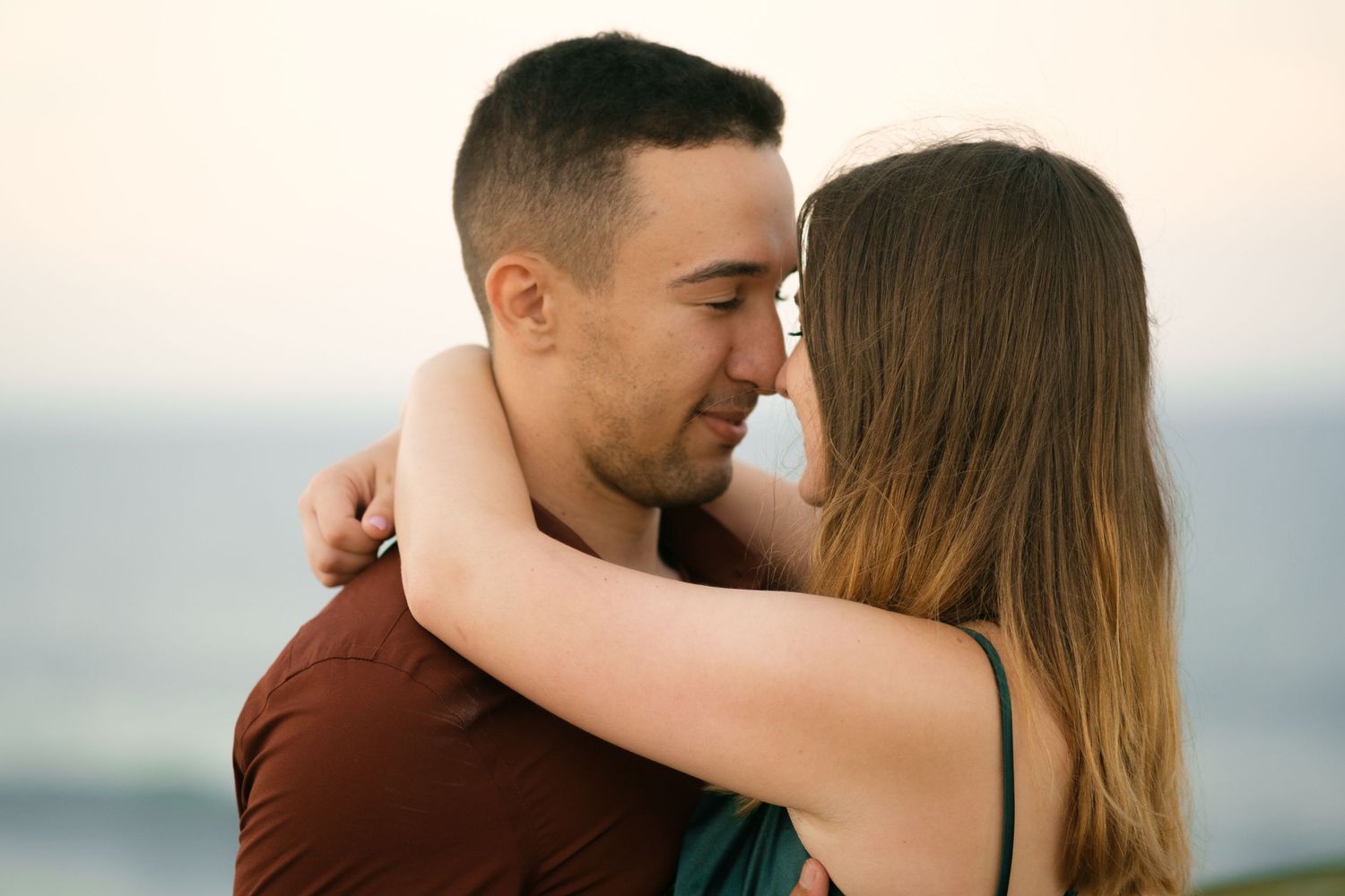 Romantic couple embracing at sunset by the ocean.