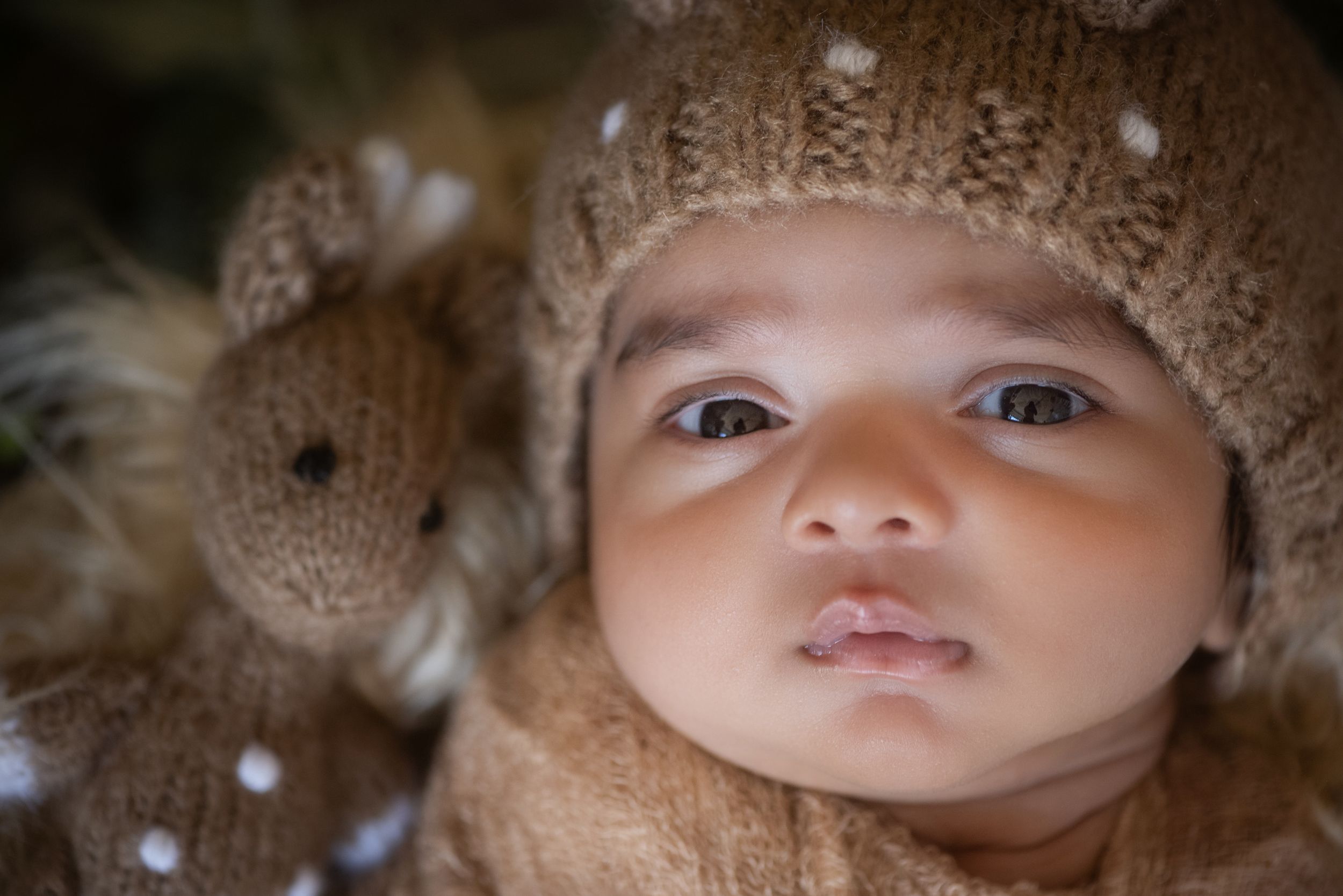 Close-up portrait of a baby wearing a knit hat with soft lighting.