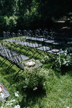 Rows of metal folding chairs set up on grass with delicate white flowers for an outdoor ceremony.