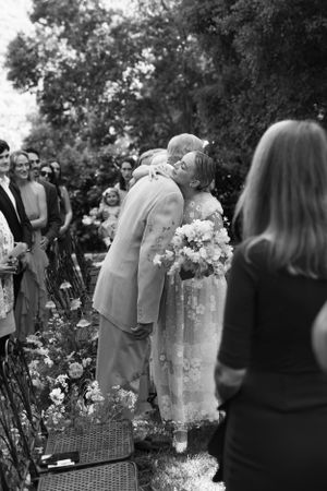 A wedding ceremony moment captured in black and white among garden flowers.