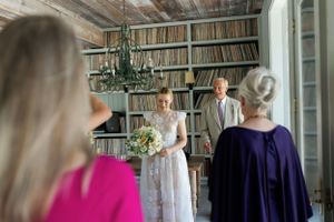 Indoor ceremony in a library room with bookshelves and chandelier.