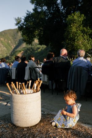 Outdoor wedding reception setting with basket of sparklers and child sitting by mountain scenery.