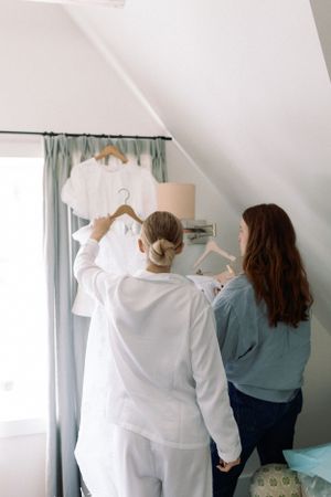 Getting ready scene with white wedding attire being prepared in a bright bedroom.