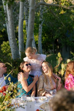 Joyful guests laughing together at an outdoor wedding reception under birch trees.