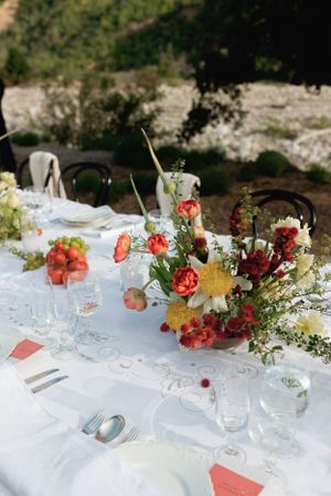 Elegant table setting with coral flowers and glassware at outdoor wedding reception.