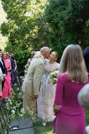An outdoor wedding celebration with guests gathered in a garden setting.