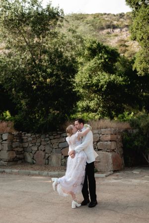 A romantic dance moment captured against a rustic stone wall background.