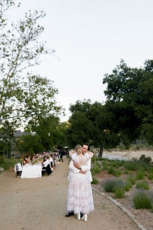 An outdoor wedding reception with long tables set up along a garden path.