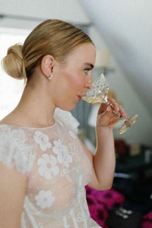 A person in a delicate lace dress sips from a crystal champagne glass in an elegant setting.
