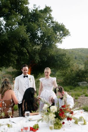 Elegant outdoor reception dining setup with white tablecloths and floral centerpieces.