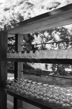Rows of glass vessels arranged on wooden shelves at an outdoor event.