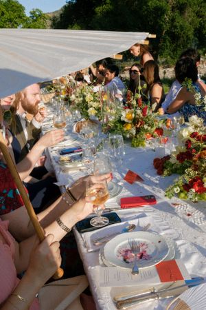 Wedding guests seated at a long table decorated with colorful flowers and glassware.