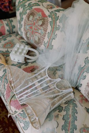 Wedding dress detail with pearl accessories on a floral patterned chair.