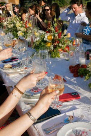 An elegant outdoor table setting with colorful floral arrangements and wine glasses.