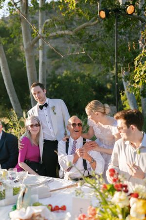 Wedding reception guests enjoying a festive outdoor dinner under string lights.