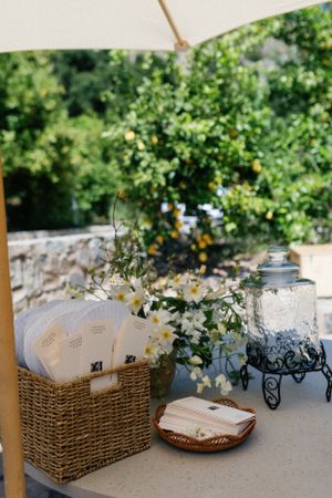 Wedding reception details with wicker basket, flowers and drink dispenser.