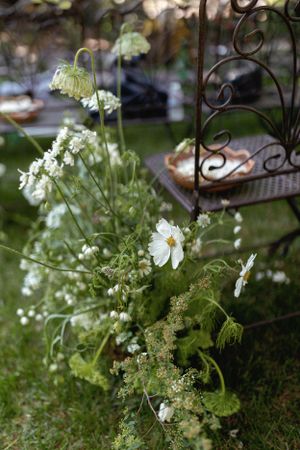 Delicate white wildflowers and greenery arrangement with decorative iron details in a garden setting.
