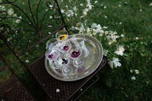 Silver tray with delicate floral arrangements sits among white flowers in a garden setting.