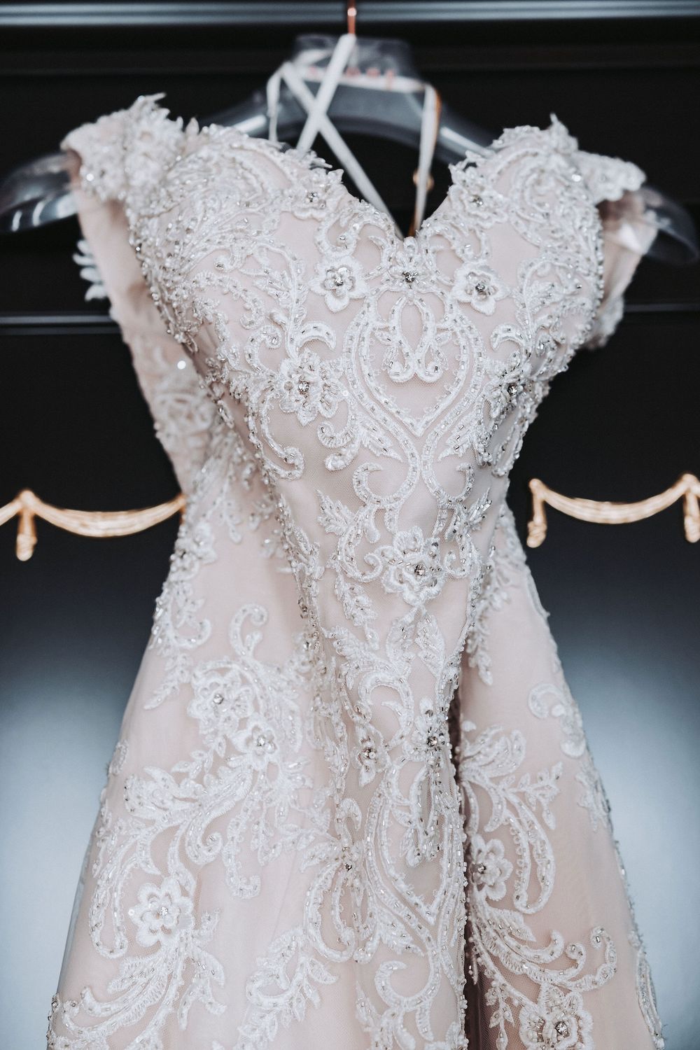 Intricate details of a white lace wedding dress bodice with delicate beading and embroidered patterns.
