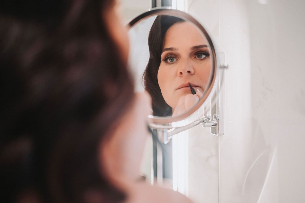 A black and white artistic portrait reflection in a circular mirror against a light background.