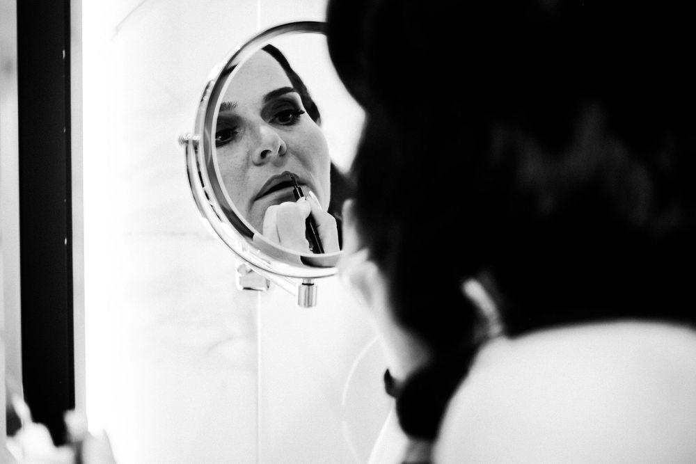 A dramatic black and white portrait shot through a circular mirror with dark shadows.