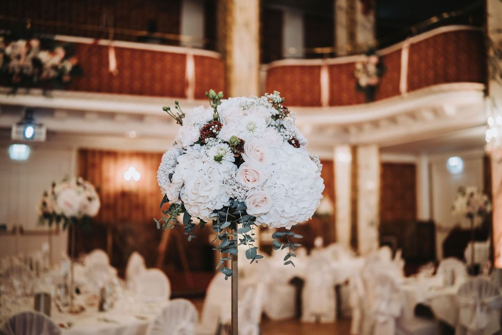 Wedding reception venue decorated with white floral centerpieces and elegant lighting.
