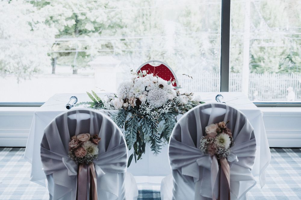 Wedding table settings with gray chair covers and floral arrangements.