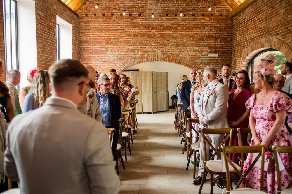 Wedding ceremony in progress inside a historic brick building with string lights overhead.