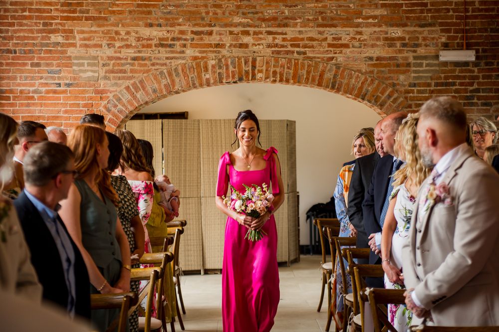 Wedding ceremony attendees gather in a rustic brick venue with natural lighting.